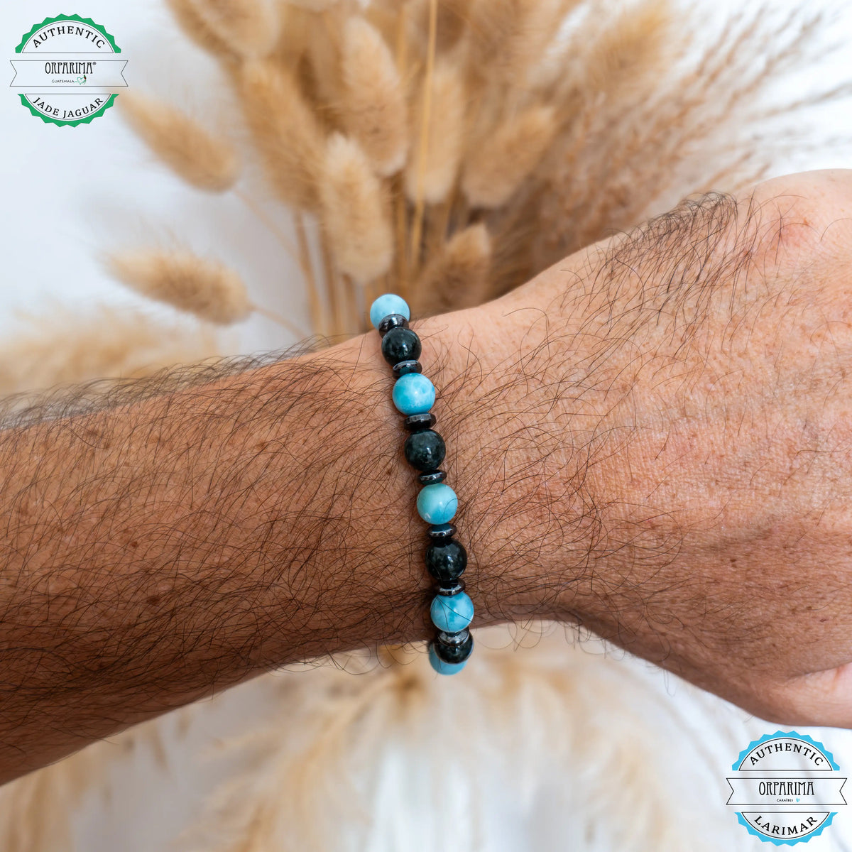 Bracelet fait avec des perles de jaspe paysage ainsi que trois perles de Larimar bleue de grande qualité. Bijou posé à plat sur fond blanc avec une breloque Orparima en acier inoxydable 316L.
