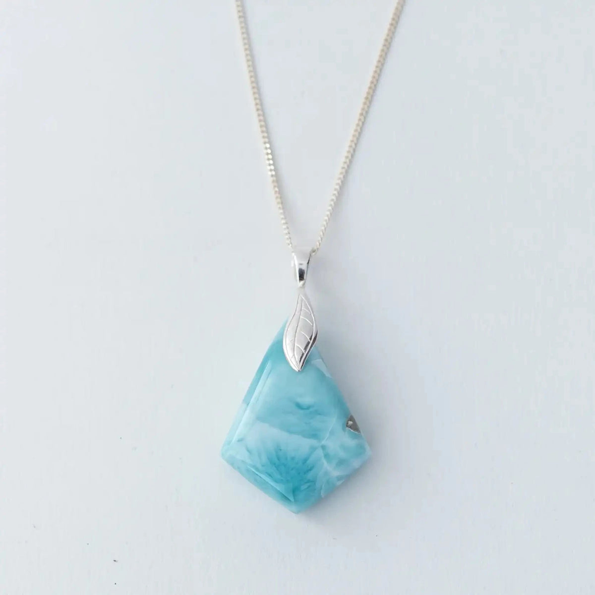 Face recto d'un collier en larimar en forme de losange monté sur une chaîne en argent 925. Pierre naturelle de République Dominicaine de couleur bleu avec différentes teintes de bleu.