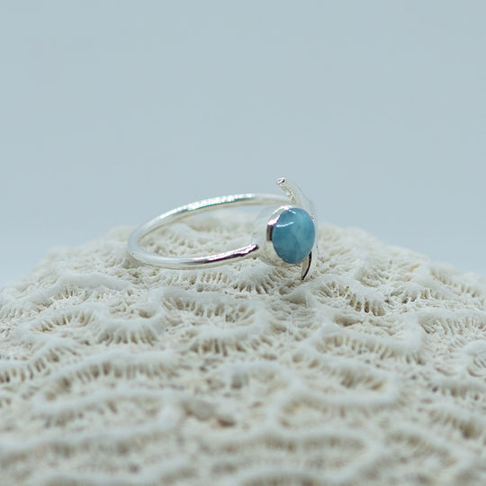 Bague en vue 3/4 posée sur un coquillage. Bijou orné d&