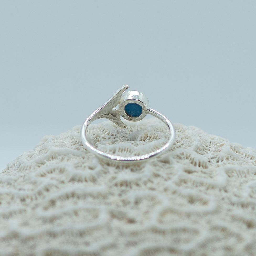Bague posée sur un coquillage vue de derrière. Bijou en argent 925 fait à la main en République Dominicaine. Une pierre de larimar ronde est incrustée dans cette bague réglable
