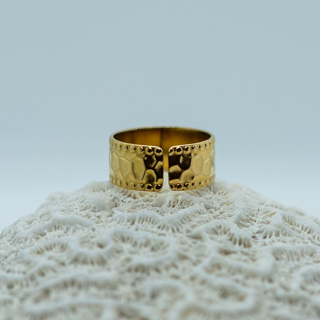 Bague texturée tendance posée de dos sur un coquillage. Bague ouverte qui permet de l&