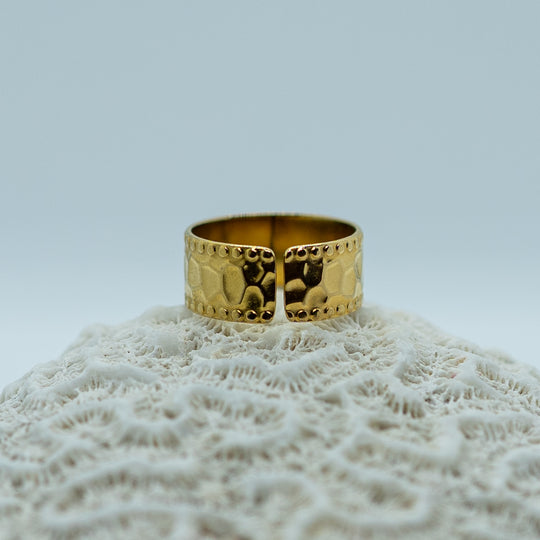 Bague texturée tendance posée de dos sur un coquillage. Bague ouverte qui permet de l&