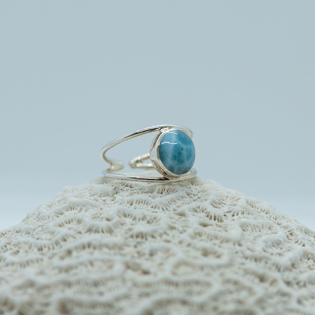Bague posée de coté sur un coquillage sur fond blanc. Bague ornée d&