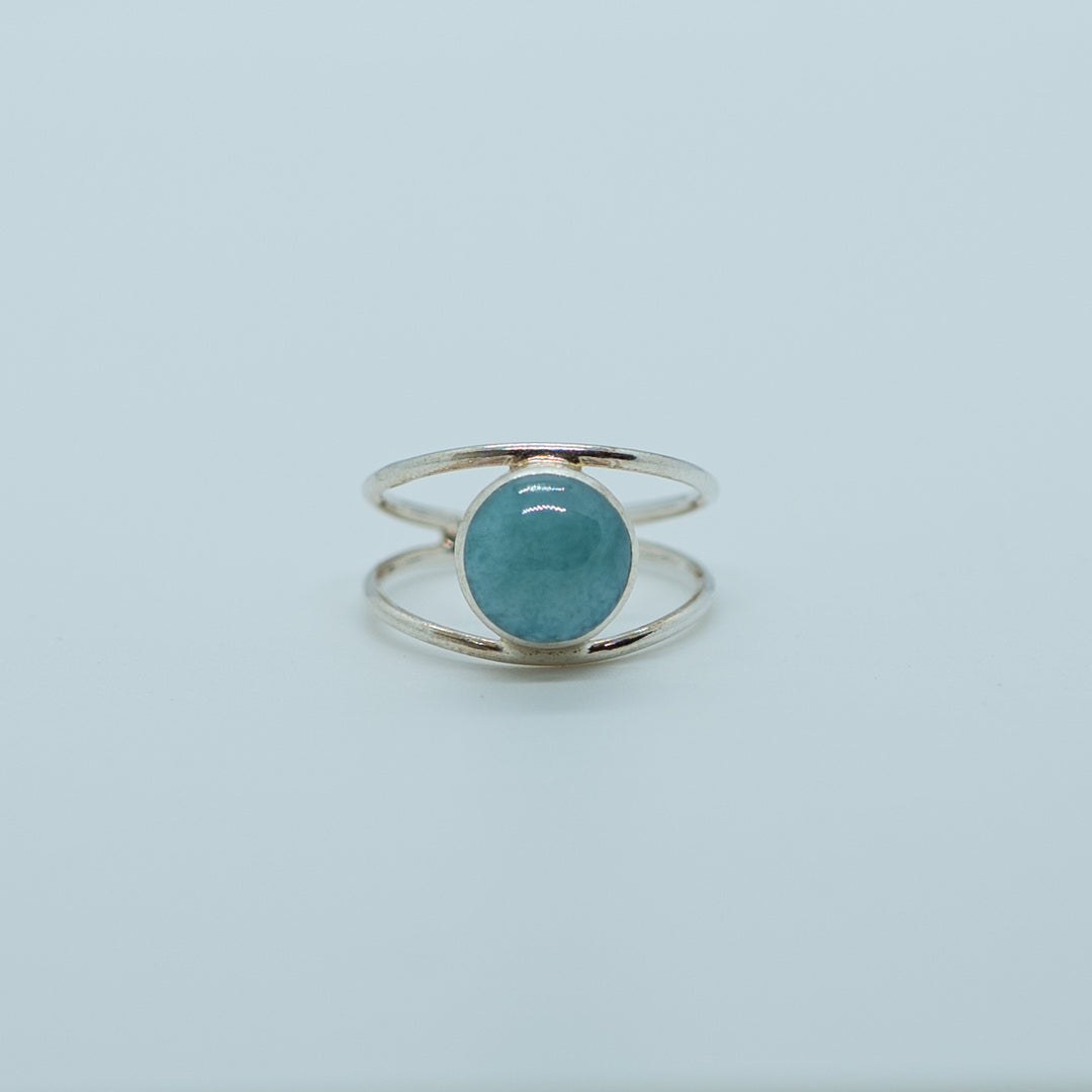 Bague en argent 925 avec une pierre de larimar ronde de couleur bleu. Structure de la bague en deux branches non fermés pour régler la bague à votre doigt.