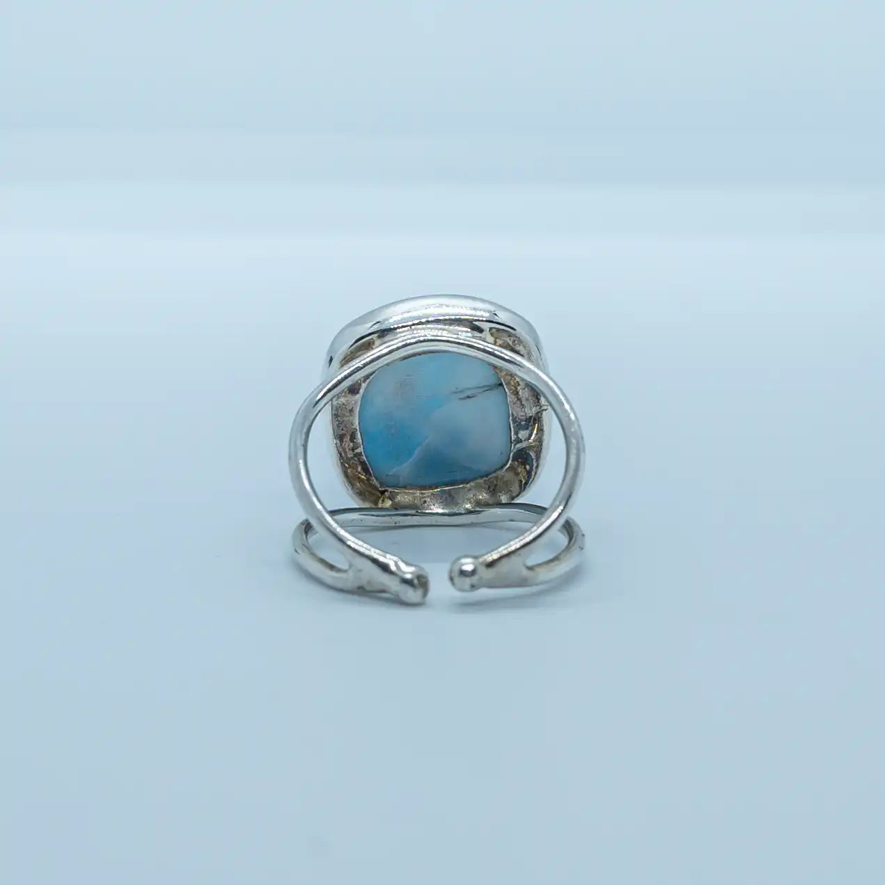 Vue de dos d'une bague d'exception en argent 925 ornée d'une pierre de larimar ronde. Bague ouverte sur le dessous pour laisser la pierre de larimar visible, bijou réglable et ajustable à votre doigt. 