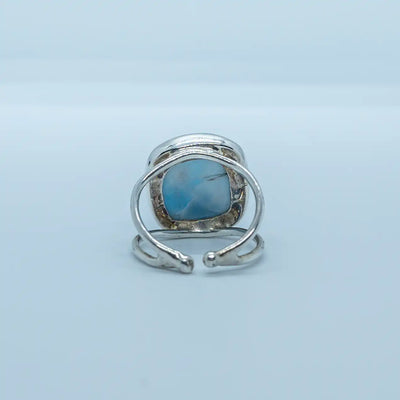 Vue de dos d'une bague d'exception en argent 925 ornée d'une pierre de larimar ronde. Bague ouverte sur le dessous pour laisser la pierre de larimar visible, bijou réglable et ajustable à votre doigt. 
