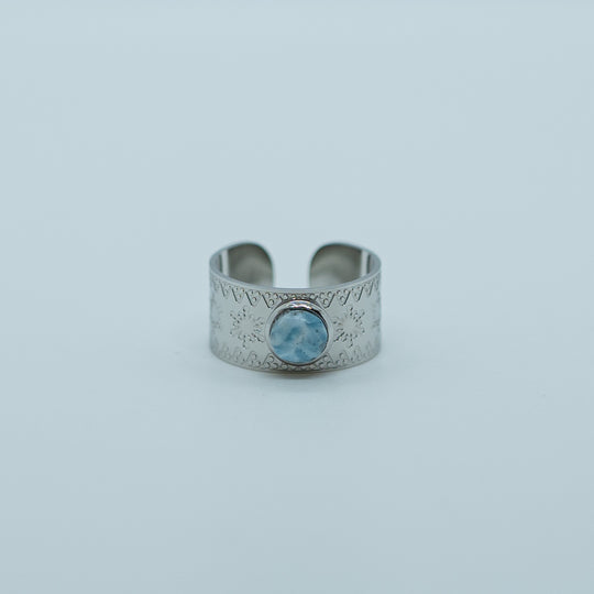 Bague de couleur argent, en acier inoxydable 316L, sur fond blanc. Pierre de larimar origine République Dominicaine sertie sur le dessus. Bijou tendance ajustable.