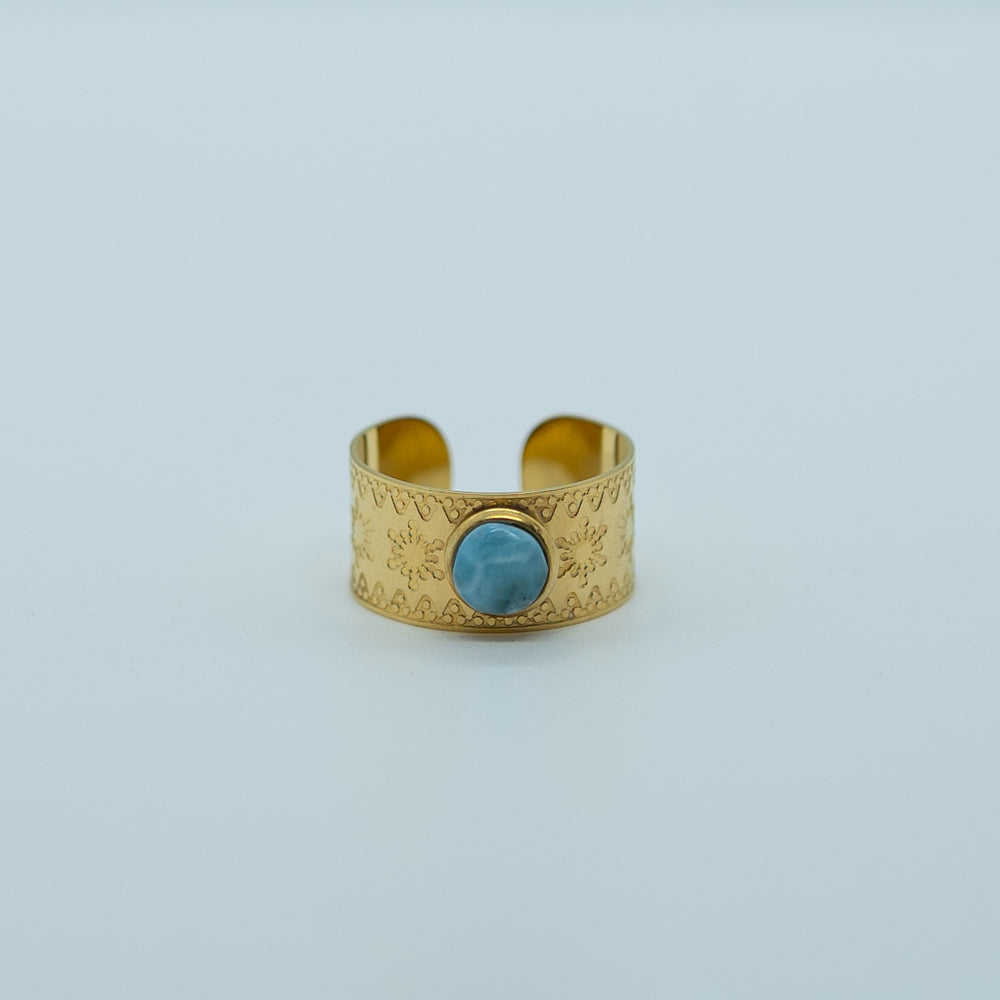Bague avec des flocons de neiges gravés, en acier inoxydable de couleur doré, ornée d'une pierre de larimar. Bague réglable non fermée ajustable.