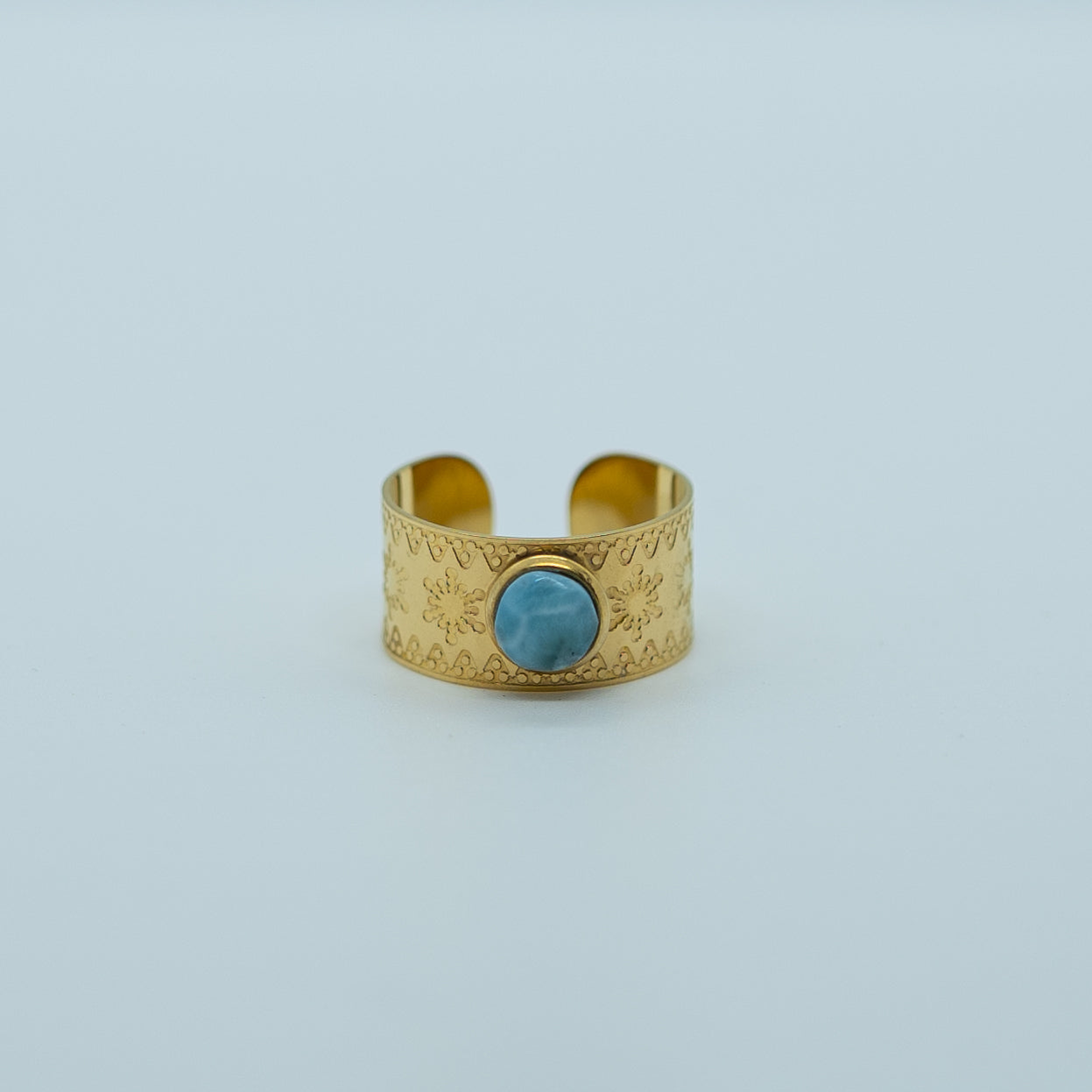 Bague avec des flocons de neiges gravés, en acier inoxydable de couleur doré, ornée d'une pierre de larimar. Bague réglable non fermée ajustable.