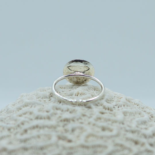 Bague posée sur un coquillage sur fond blanc. Bague en argent 925 ouverte sur le bas de l&