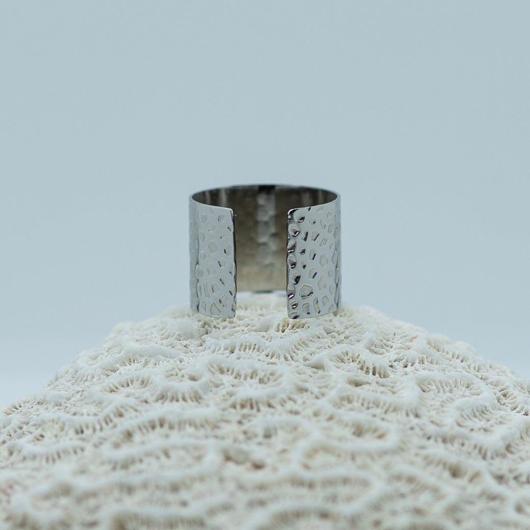 Bague texturée de couleur argent prise de dos, posée sur un coquillage. Bague réglable tendance et originale.