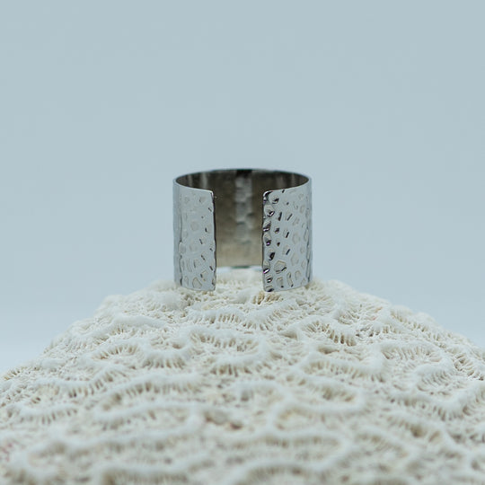 Bague texturée de couleur argent prise de dos, posée sur un coquillage. Bague réglable tendance et originale.