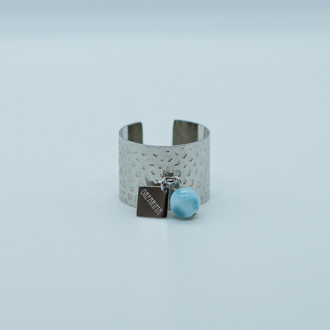 Bague avec une breloque orparima et une perle de larimar de 6mm de diamètre. Bague texturé argenté en acier inoxydable 316L réglable.