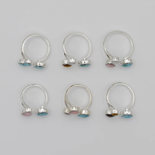 6 Bagues réglables vues du dessus avec 3 cabochons ronds sertis sur chacune, cabochons en Larimar, Ambre, Nacre et Lambi.