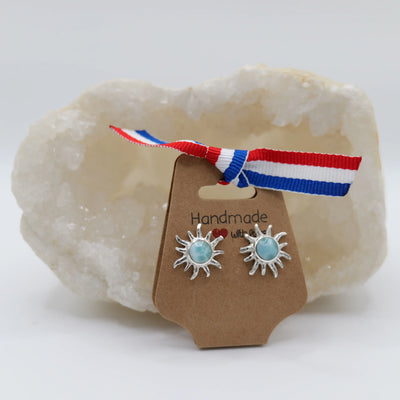 Magnifique pierre de Larimar de couleur bleue de forme ronde, montée au centre d'une paire de boucles d'oreilles en argent 925 en forme de soleil.