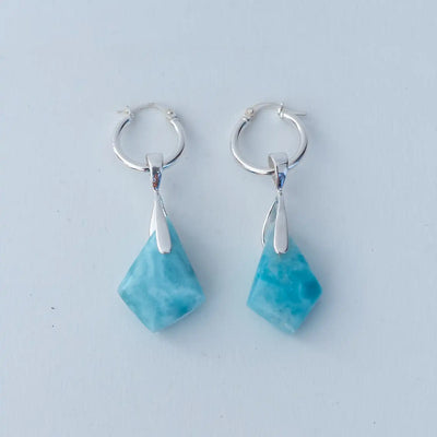 Vue de dos d'une paire de boucles d'oreilles créoles avec deux pierres de larimar bleu taillées en losange. Bijou en argent 925 et en pierres naturelles