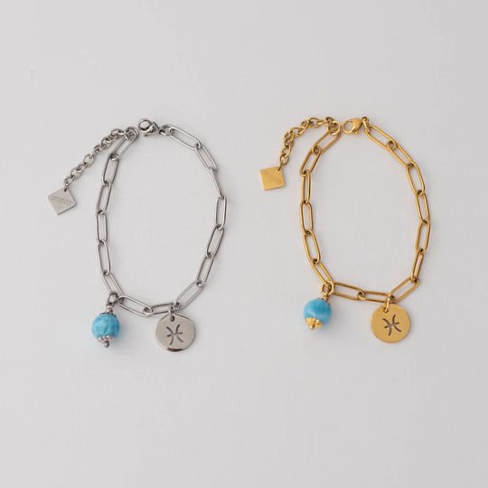 Photo de deux bracelet avec une breloque orparima attachée au fermoir. Bracelet de gauche en acier inoxydable 316L argent, bracelet de droite en acier inoxydable 316L doré. Breloque signe astrologique et perle de larimar attaché à chaque bracelet.