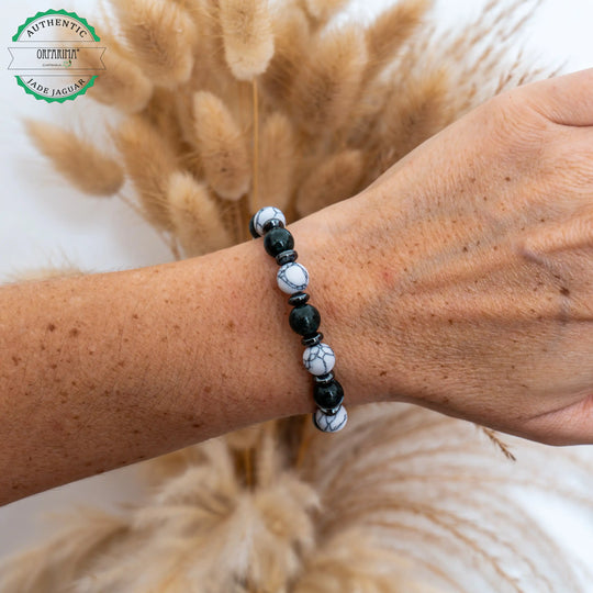 Bracelet avec des perles de Howlite blanche et de Jade Jaguar vertes foncées séparées par des intercalaires en hématite de couleur noire. Bracelet en fil élastique fait à la main en République Dominicaine.