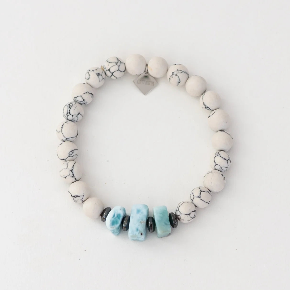 Bracelet en howlite blanche avec cinq fragments de larimar de République Dominicaine et des intercalaires en hématite. Bracelet en fli élastique resistant à l'eau et à la transpiration.