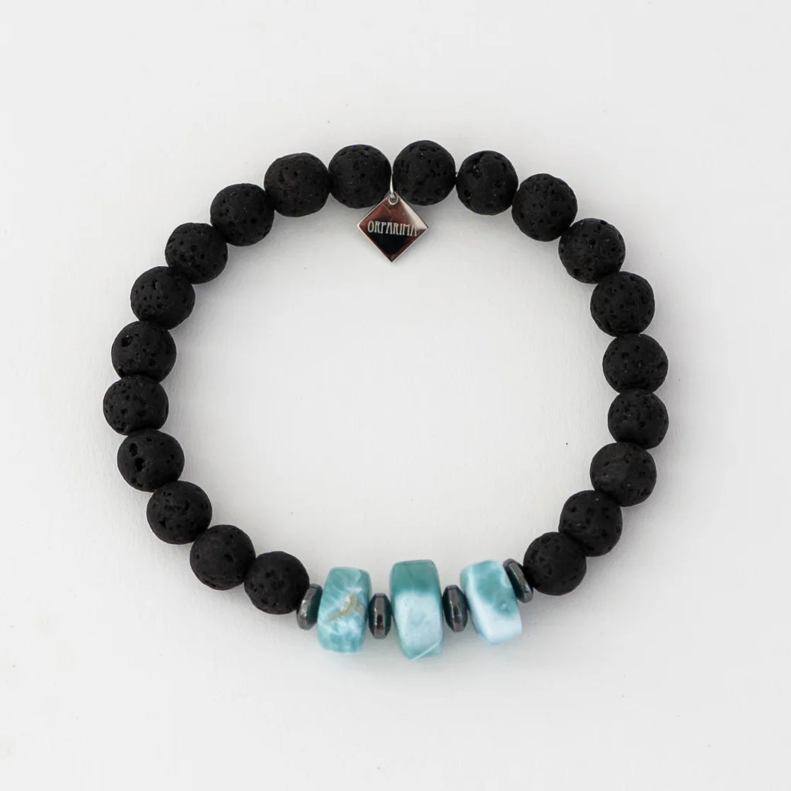 Bracelet noir en pierre de lave avec trois fragments de larimar de forme carrée. Bracelet avec une breloque orparima.