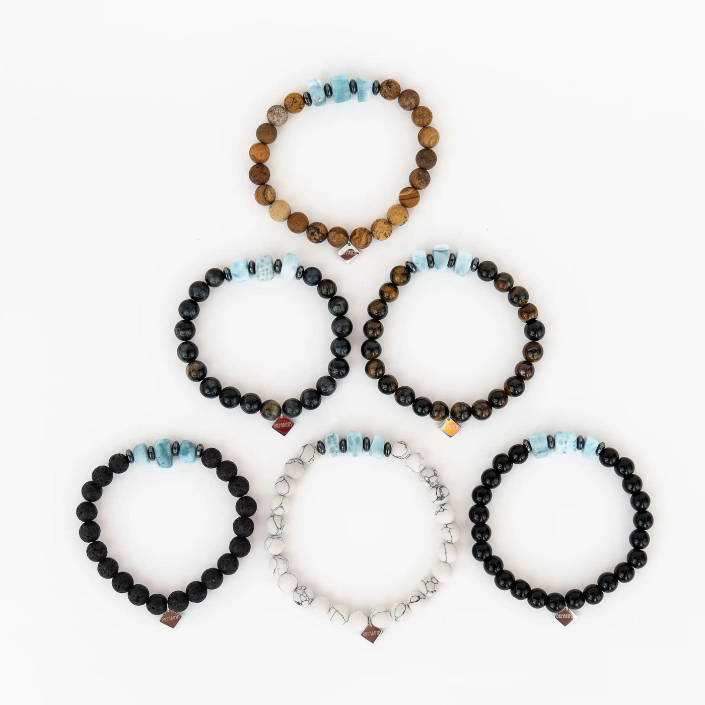Cinq bracelets avec 3 fragments de larimar chacun, associés à l'un des cinq pierre suivante : howlite, pierre de lave, obsidienne, oeil du tigre, oeil du faucon et Jaspe paysage. Bracelet avec une breloque orparima.
