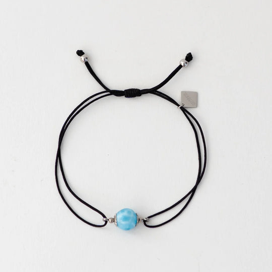 Bracelet en cordon noir avec une perle de larimar bleu faite à la main par notre artisan dominicain. Breloque orparima pendante. Resiste à l&