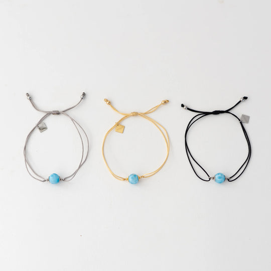 Bracelets cordon disponibles en trois couleurs différentes, argenté, doré ou noir. Bracelet avec chacun une perle de larimar et une breloque orparima en pendant.