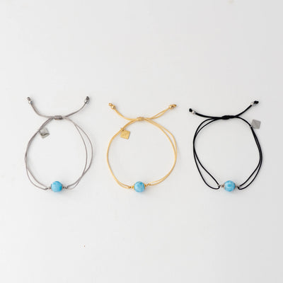 Bracelets cordon disponibles en trois couleurs différentes, argenté, doré ou noir. Bracelet avec chacun une perle de larimar et une breloque orparima en pendant.