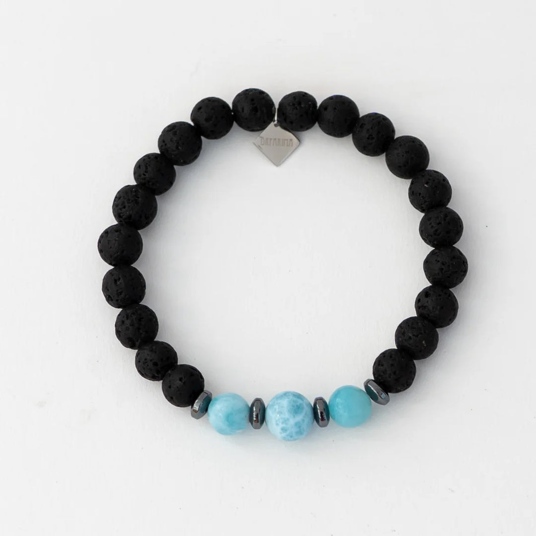 Bracelet en fil élastique constitué de perles de pierre de lave ainsi que de trois perles de larimar origine République Dominicaine. Bracelet avec une breloque orparima.