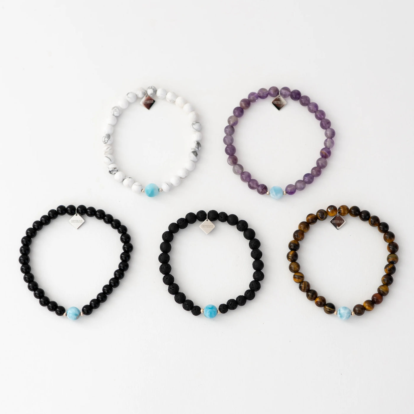 Photo de cinq bracelets avec des perles de 6mm et une perle de larimar de 6mm. bracelet en howlite, pierre de lave, obsidienne, oeil du tigre ou améthyste. Larimar origine République Dominicaine.