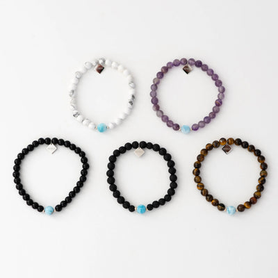 Photo de cinq bracelets avec des perles de 6mm et une perle de larimar de 6mm. bracelet en howlite, pierre de lave, obsidienne, oeil du tigre ou améthyste. Larimar origine République Dominicaine.