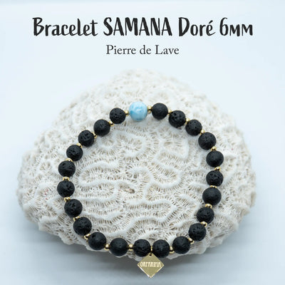 Bracelet en pierre de lave posé sur un coquillage blanc. Ce bracelet comporte une perle de Larimar de 6mm de République Dominicaine. Les perles sont séparées par des petites perles en acier inoxydable de couleur doré. Bijou fait à la main.