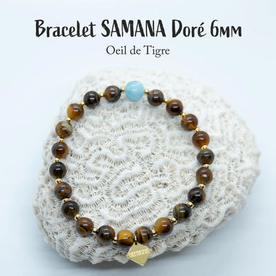Bracelet en fil élastique avec des perles d’œil du tigre de 6mm et une perle de Larimar. Bijou posé sur un coquillage blanc, fait à la main en République Dominicaine.