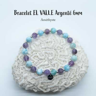 Bracelet posé sur un coquillage, fait à moitié en améthyste et l'autre moitié en perles de Larimar. Ce bracelet est en fil élastique et peut être fait en plusieurs tailles, il possède une breloque en acier inoxydable avec orparima gravé dessus. Les perles sont en 6mm.
