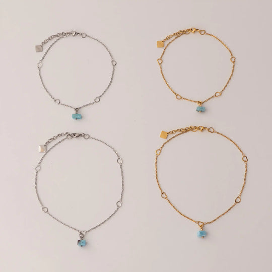 Quatre chaînes de chevilles dans deux formats différents avec une perle de larimar en pendant. Chaînes avec une extension et une breloque orparima.