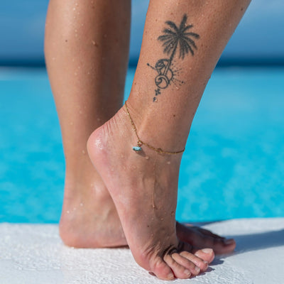 Photo du bas des jambes d'une femme portant une chaîne de cheville en acier inoxydable 316L avec un fragment de larimar bleu provenant de République Dominicaine.