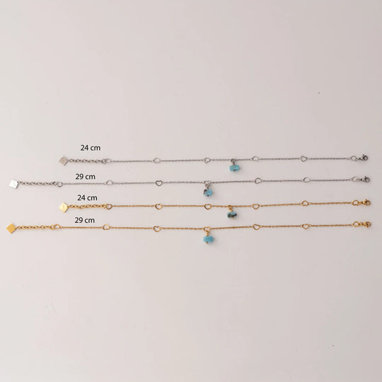 Quatre modèles de chaînes de chevilles de 24cm et 29cm de couleur argent ou doré avec sur chacune un fragment de larimar bleu en pendant. Chaque modèle possède une chaîne d&