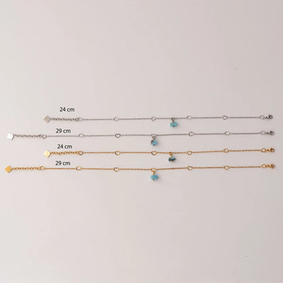 Quatre modèles de chaînes de chevilles de 24cm et 29cm de couleur argent ou doré avec sur chacune un fragment de larimar bleu en pendant. Chaque modèle possède une chaîne d'extension avec une breloque orparima.