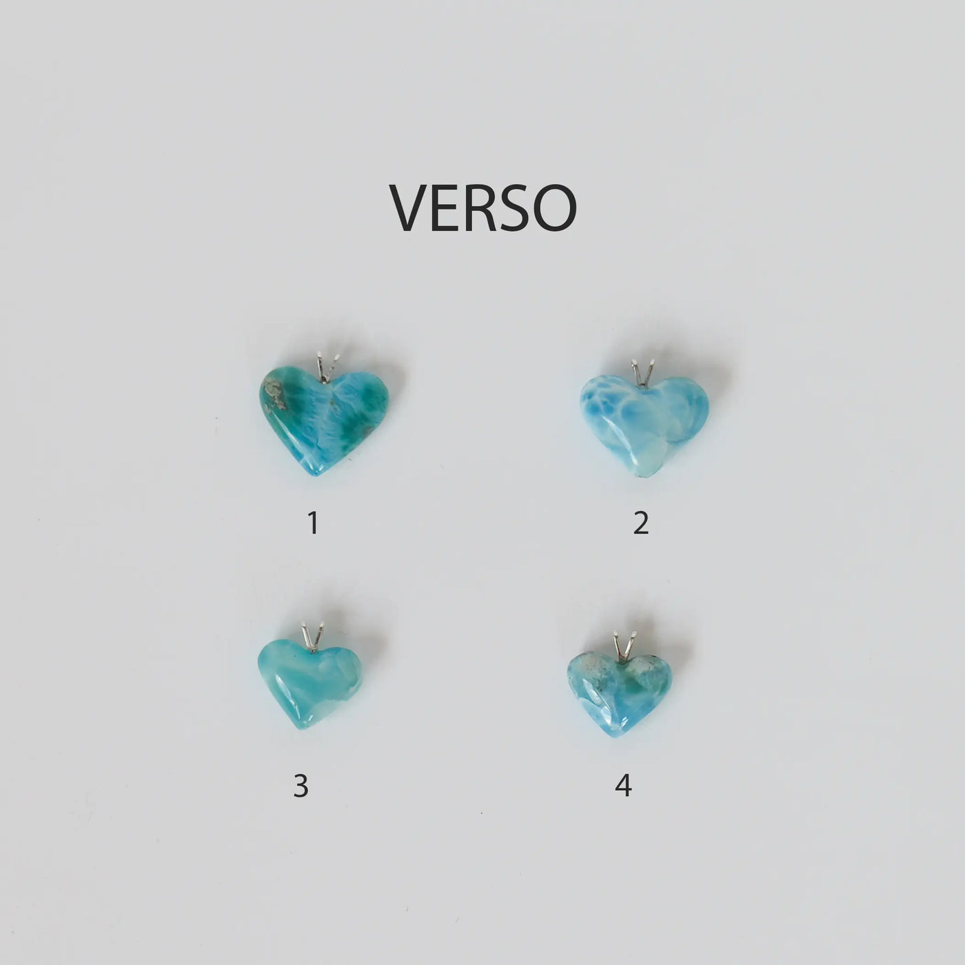 pendentifs en larimar au nombre de quatre et taillés en forme de cœur, posés sur un fond uni blanc. Bijoux faits à la main en République Dominicaine.