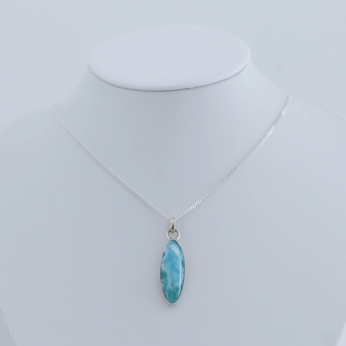 Collier en argent 925 avec son cabochon en Larimar bleu monté sur une chaîne et présenté sur un bustier blanc.