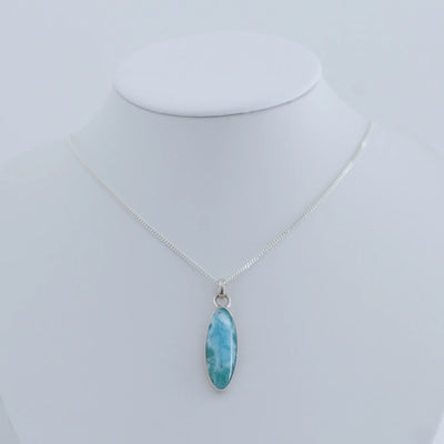 Collier en argent 925 avec son cabochon en Larimar bleu monté sur une chaîne et présenté sur un bustier blanc.