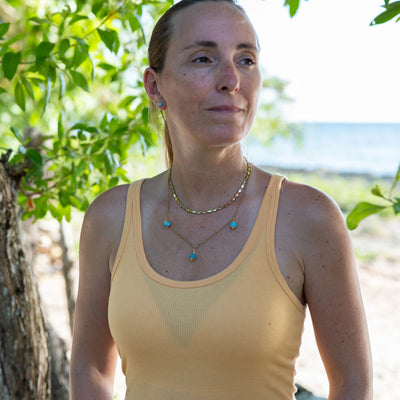 Collier avec deux chaînes différentes en terme de forme et de longueur, chacune en acier inoxydable doré 316L, avec trois perles de larimar bleu sur la chaîne la plus longue.