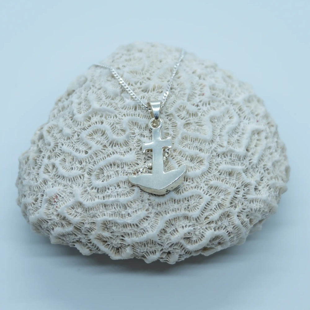 Collier en argent 925 posé sur un coquillage de type corail sur fond blanc. Bijou avec un pendentif vue sur sa face verso. 