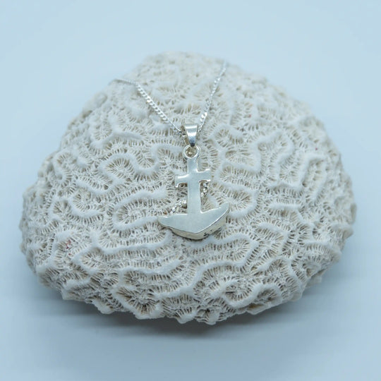 Collier en argent 925 posé sur un coquillage de type corail sur fond blanc. Bijou avec un pendentif vue sur sa face verso. 