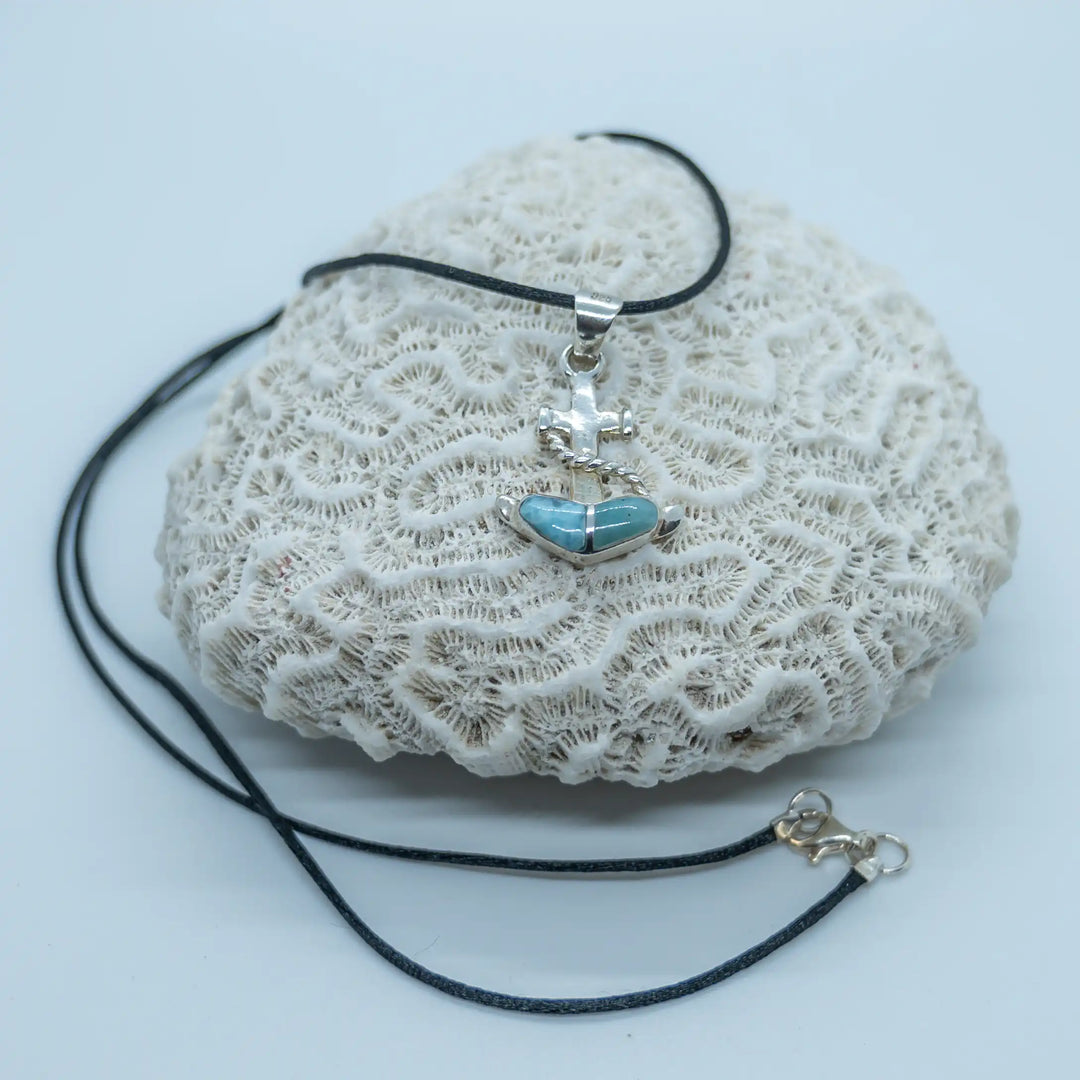 Bijou fait à la main représentant une ancre de bateau avec une pierre de Larimar bleue. Le collier est un fil noir et le pendentif est fait en argent 925.