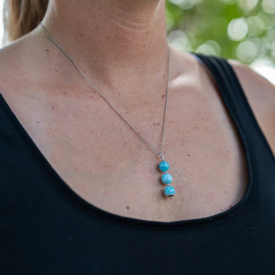 Collier argenté en acier inoxydable 316L et son placage PVD coating résistant à la corrosion. Collier avec trois perles de larimar bleu pendante le long d&