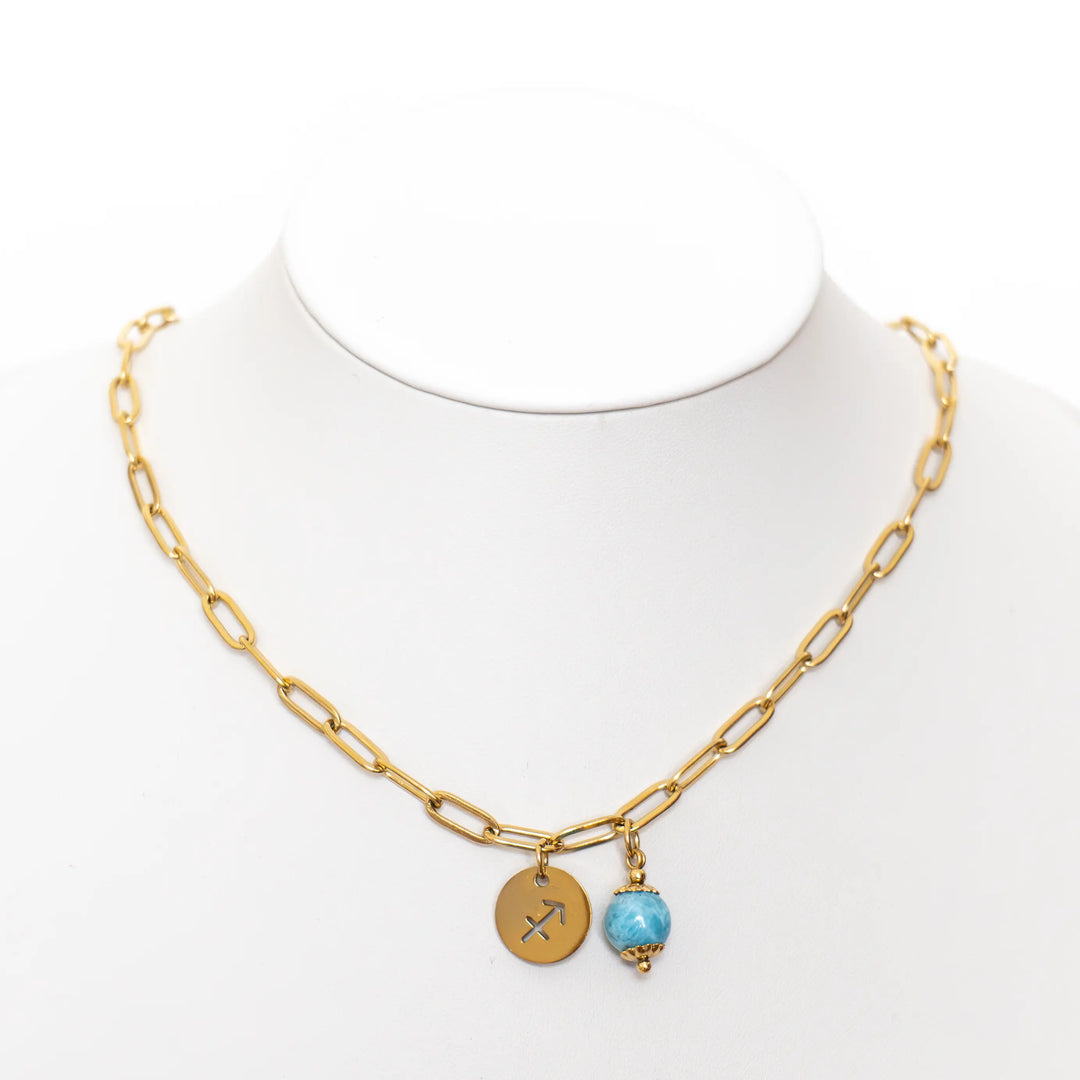 Présentoir blanc sur fond blanc avec un collier à la maille large en acier inoxydable doré avec sa perle de Larimar d&