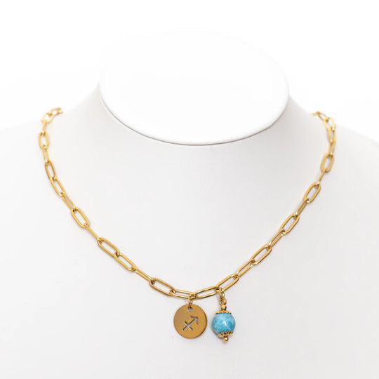 Présentoir blanc sur fond blanc avec un collier à la maille large en acier inoxydable doré avec sa perle de Larimar d&