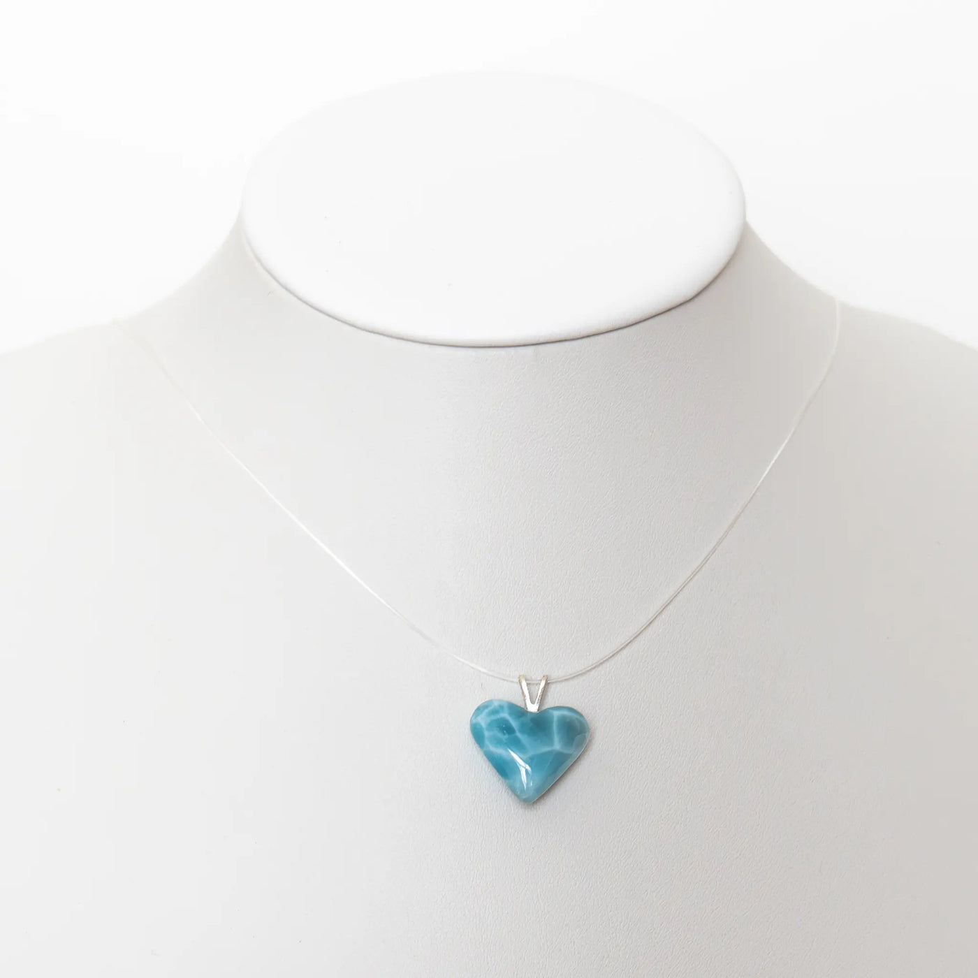 Cœur taillé dans la pierre naturelle de Larimar de République Dominicaine monté sur un fil transparent pour être porté en collier. Qualité exceptionnelle du Larimar, bijou fait à la main en République Dominicaine.