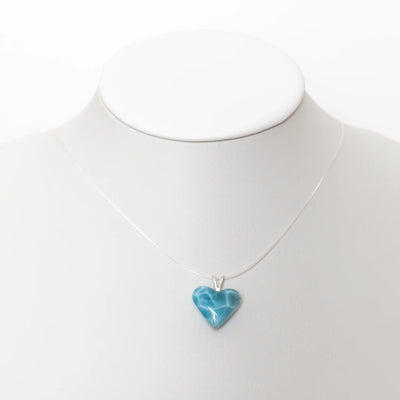 Cœur taillé dans la pierre naturelle de Larimar de République Dominicaine monté sur un fil transparent pour être porté en collier. Qualité exceptionnelle du Larimar, bijou fait à la main en République Dominicaine.